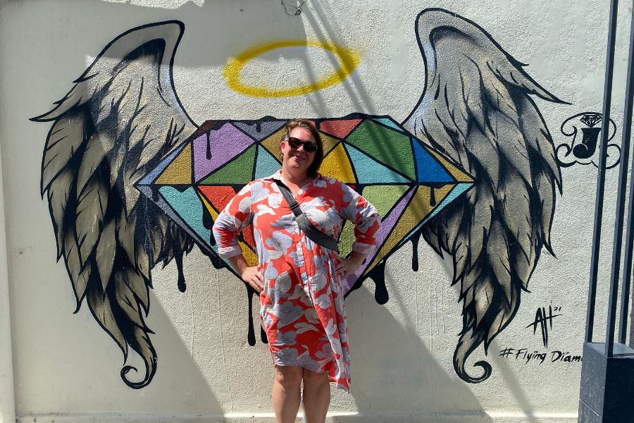 Kimberly at a wall in Thailand with angel wings painted on it