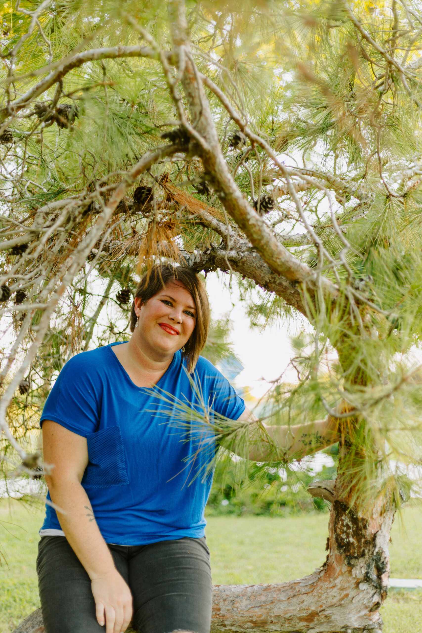 Kimberly sitting on a tree in Cyprus with a blue shirt and black pants